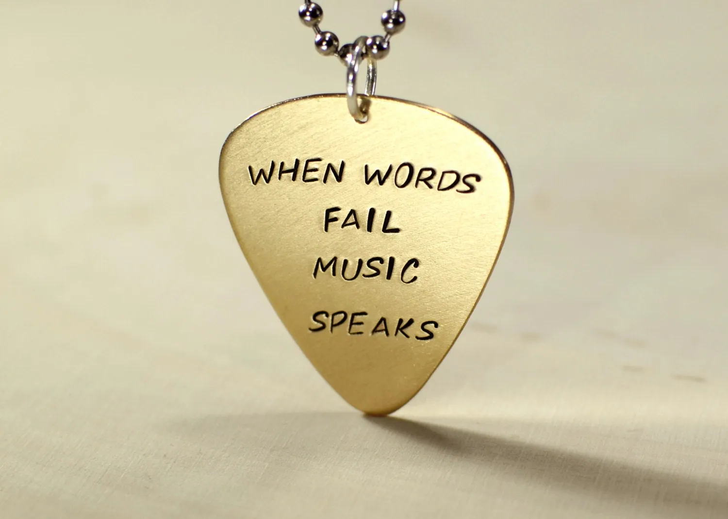 When words fail music speaks on a 14K solid yellow gold guitar pick necklace