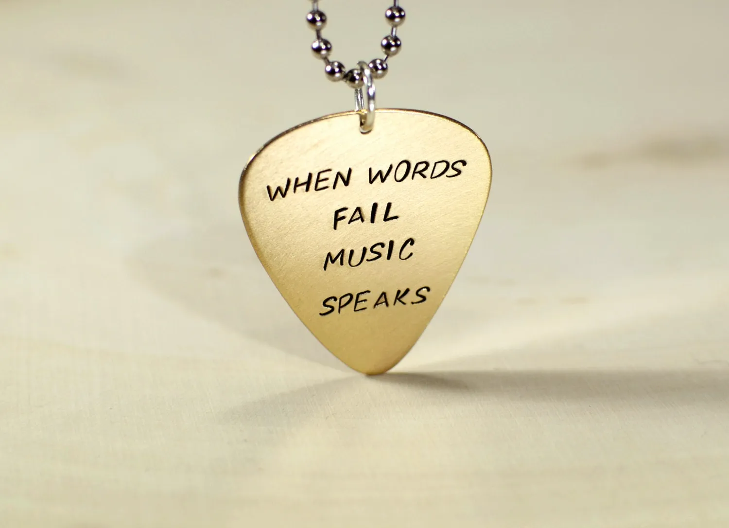 When words fail music speaks on a 14K solid yellow gold guitar pick necklace