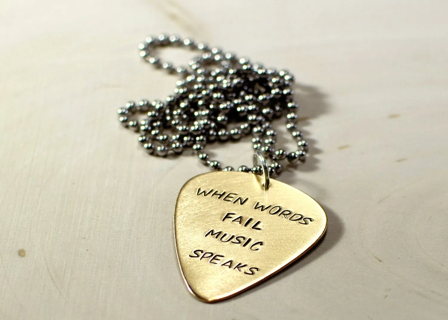 When words fail music speaks on a 14K solid yellow gold guitar pick necklace